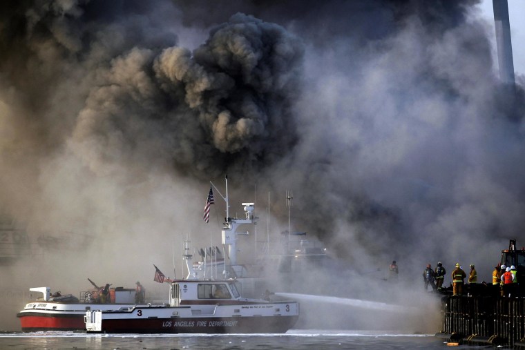 Image: Los Angeles firefighters watch as smoke from a dock fire continues to rise at the Port of Los Angeles
