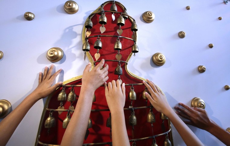 Image: Blind Thai students reach for bells in the shape of a Buddha, part of the exhibit on the Thai king's royal boat, in a pilot project to develop tourism for the blind and visually impaired in the Thai Kingdom