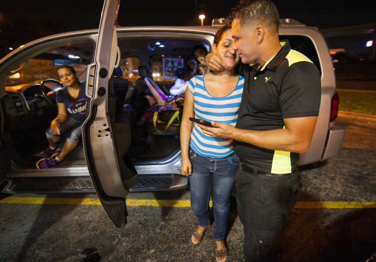 Image: Cuban migrant Mailin Perez  embraces with her husband Jose Caballero after arriving via Mexico at a bus station in Austin