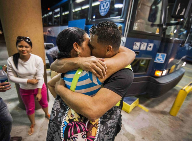 Image: Cuban migrant Mailin Perez embraces with her husband Jose Caballero (2nd L) after arriving via Mexico at a bus station in Austin