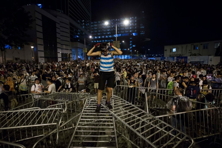 Image: A pro-democracy student stands on railings during a rally outside the government headquarters in Hong Kong