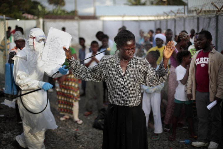 Image: A woman being discharged from the Island Clinic Ebola treatment center in Monrovia, Liberia, is sprayed with disinfectant