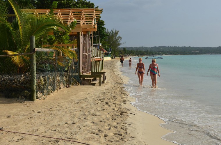 Image: Tourists walk along a badly eroding patch of resort-lined beach in Negril, Jamaica