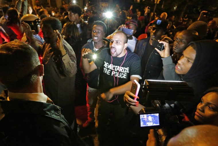 Image: Crowds confront police near the scene in south St. Louis where a teen was fatally shot by an off-duty police officer