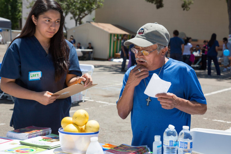 Image: Lorenia Gutierrez talks to a health fair patient about making good nutritional choices.