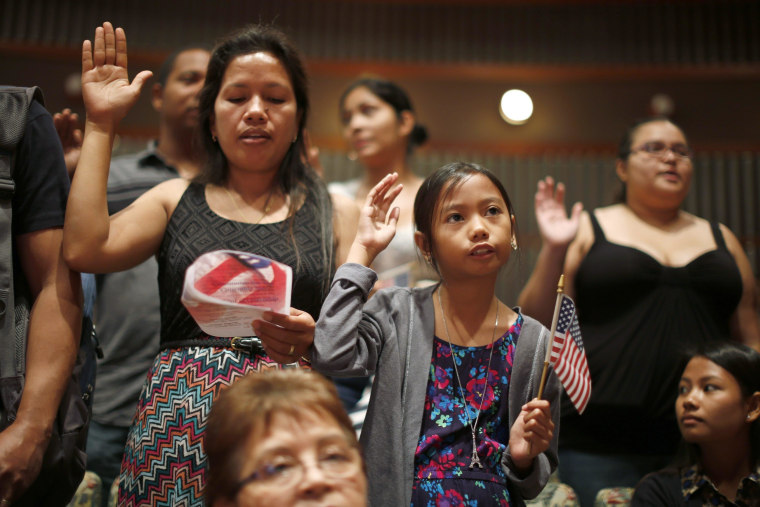 Image: People say the pledge of allegiance at a U.S. citizenship ceremony for 80 immigrant children and youths in Los Angeles