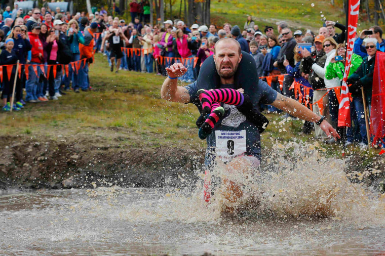 Image: Eventual winners Jesse Wall carries Christina Arsenault through the water pit while competing in the North American Wife Carrying Championship at Sunday River ski resort in Newry