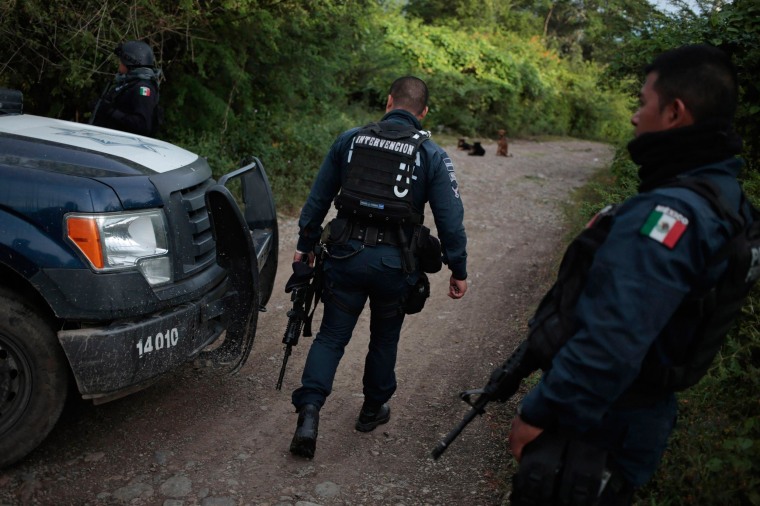 Image: Federal police walk on a road at an area near clandestine graves at Pueblo Viejo, in the outskirts of Iguala, southern Mexican state of Guerrero