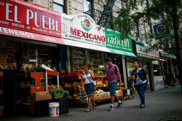 Image: People pass by a Mexican grocery store in Harlem, N.Y., on Aug. 10.