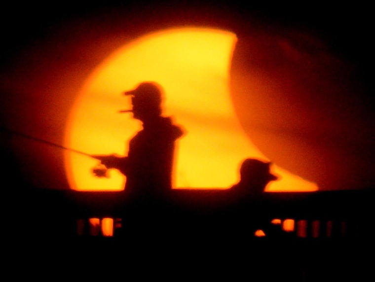 Image: Fishermen try their luck from the M.B. Miller County Pier during a partial solar eclipse