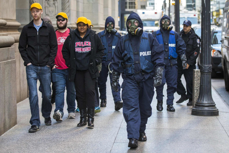 Image: Toronto Police officers wearing gas masks walk down King Street in the heart of the financial district during a mock crisis response exercise in Toronto