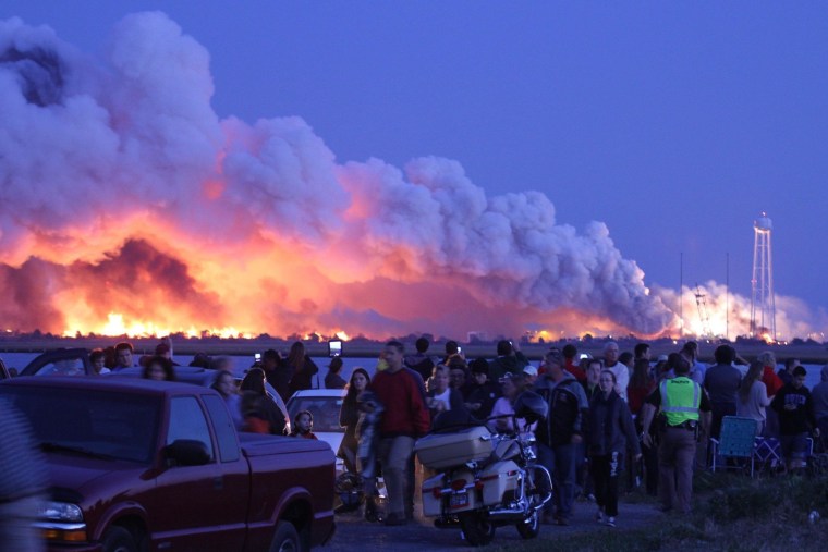 Image: People who came to watch the launch walk away after an unmanned rocket owned by Orbital Sciences Corporation exploded