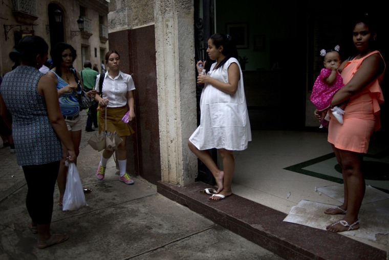 In this Oct. 22, 2014 photo, a pregnant woman a pregnant woman drinks a soft drink at the entrance of a special maternity unit for high-risk pregnancies in Havana, Cuba. The island nation has long prided itself on care of pregnant women and newborns, and officials often boast of an infant mortality rate lower than that of the United States. (AP Photo/Ramon Espinosa)