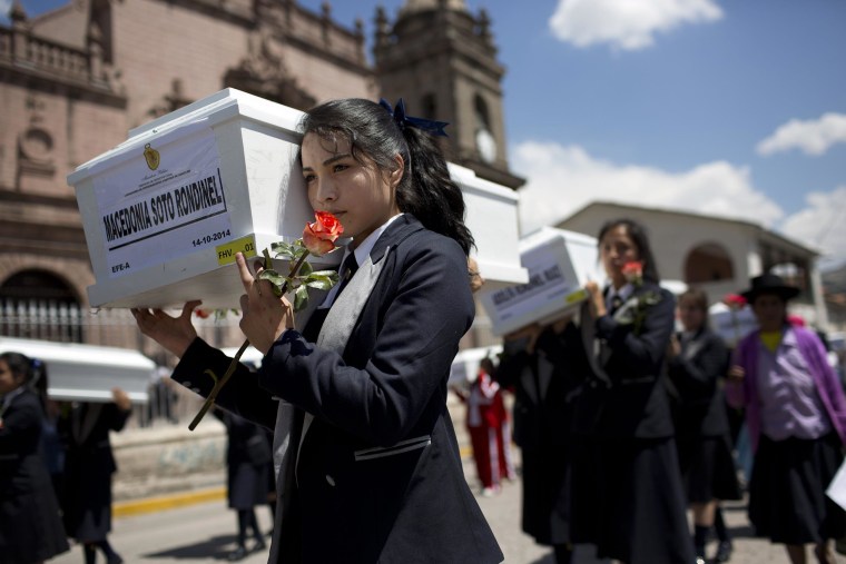Image: A student carries a coffin containing the exhumed remains of a victim of the country's dirty war, in a procession in Huamanga, Peru