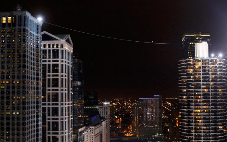 Image: Daredevil Nik Wallenda walks along a tightrope between two skyscrapers suspended 500 feet above the Chicago River