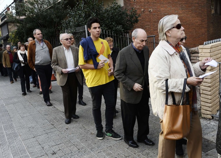 Image: People queue outside a polling station in Barcelona