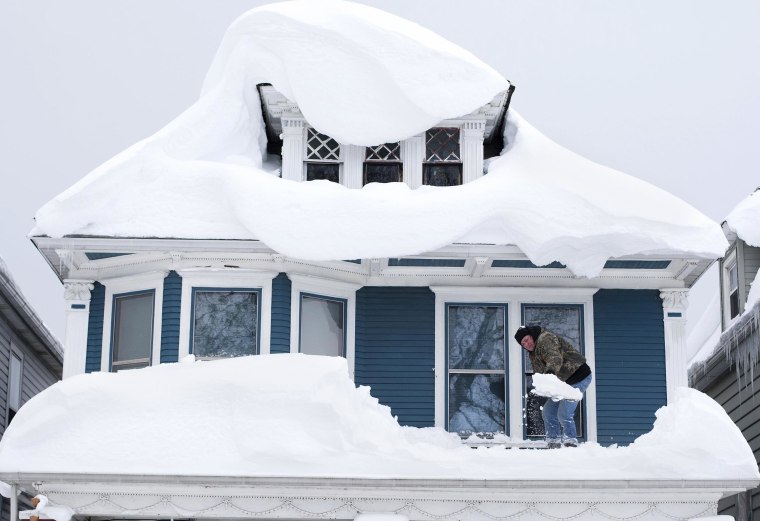 Image: Tom Wilczak shovels snow from the roof of his home following a storm in Buffalo