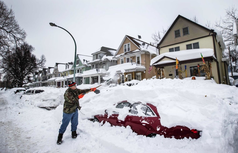 Image: Thomas Wisniewki digs his car out of snow following a massive snow storm in Buffalo