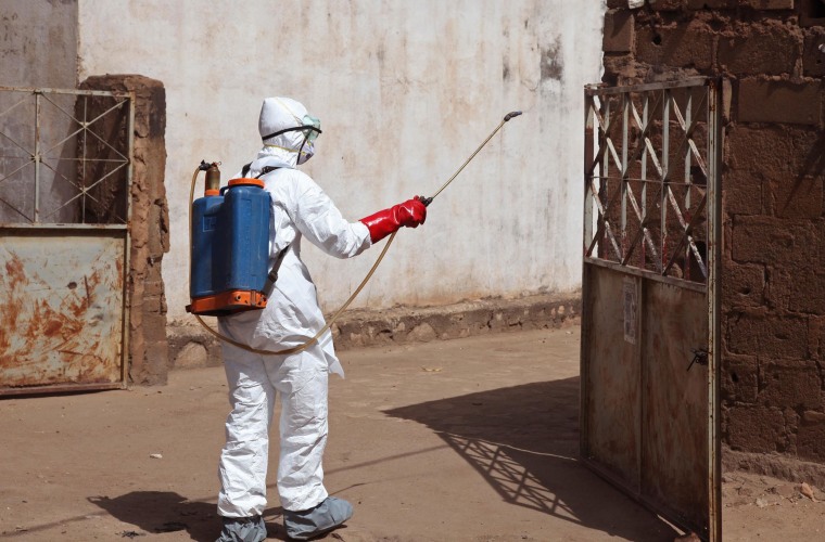 A health worker sprays disinfectant near a mosque after the body of a man suspected of dying from the Ebola virus was washed inside in Bamako, Mali, on Nov. 14.
