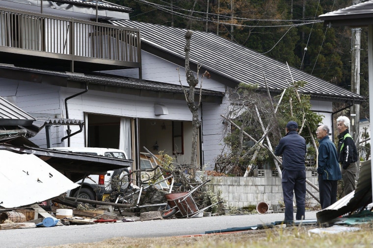 Image: Local residents look at a collapsed house after a strong earthquake hit the area the night before, in Hakuba