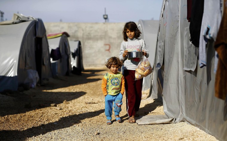 Image: Kurdish refugee children from the Syrian town of Kobani carry food for breakfast