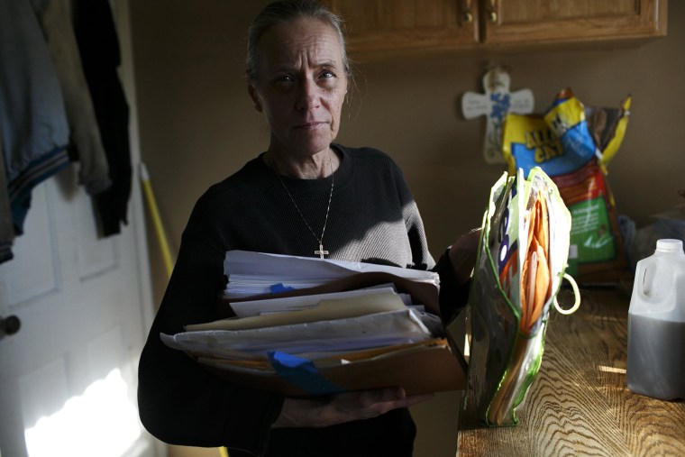 Image: Donna Cox goes through a pile of paperwork and bills at her home in Cleveland, OH