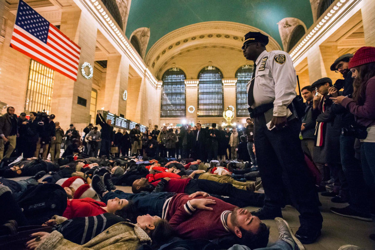 Image: A police officer stands over activists, demanding justice for the death of Eric Garner, as they stage a 'die-in' during rush hour at Grand Central Terminal in the Manhattan borough of New York