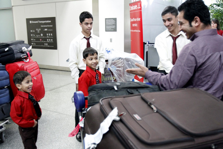 Image: Mohammad Usafi, right, greets his brothers as they come out of customs at San Francisco International Airport