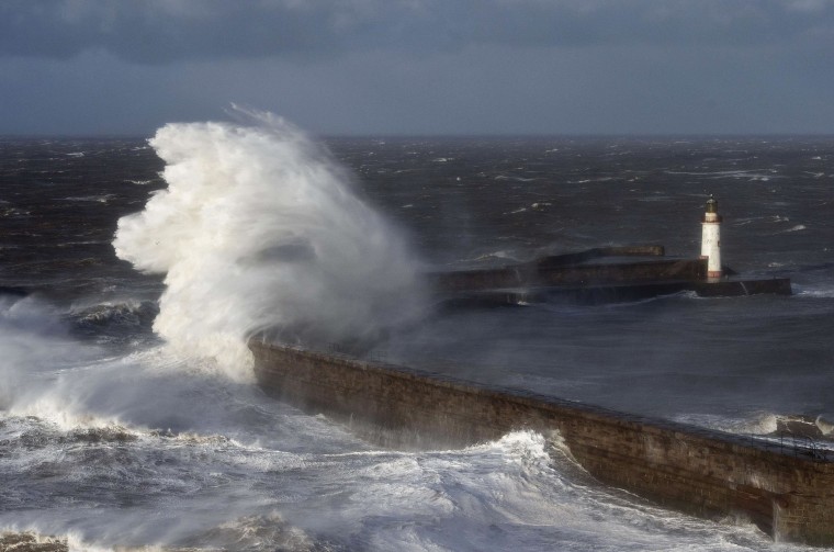Image: Large waves crash over the harbor wall in the town of Whitehaven in Cumbia