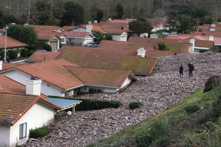 Image: A TV news crew files a report behind damaged homes after a mud slide in Camarillo Springs, California