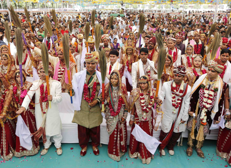 Image: Newly-married Hindu couples hold brooms as they pledge to clean their houses, after taking their wedding wows during a mass marriage ceremony in the western Indian city of Ahmedabad