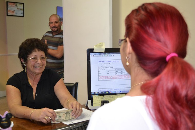 At Havana Centro Travel Agency a customer purchases a ticket for Cuba while another customer waits to be helped.