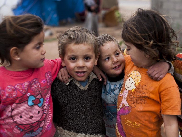 Murad, poses with friends, all Syrian refugees, near his family’s tent , in Reyhanli, southern Turkey.