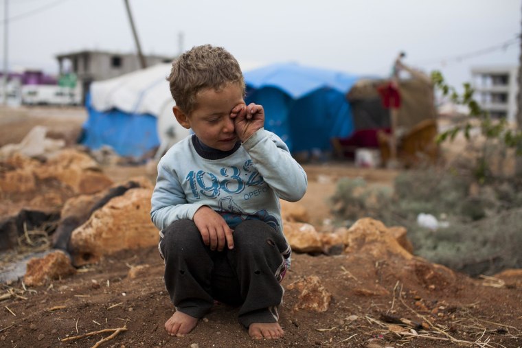 Murad tries to get sand from his eyes after playing with friends near his family’s tent in Reyhanli, southern Turkey.