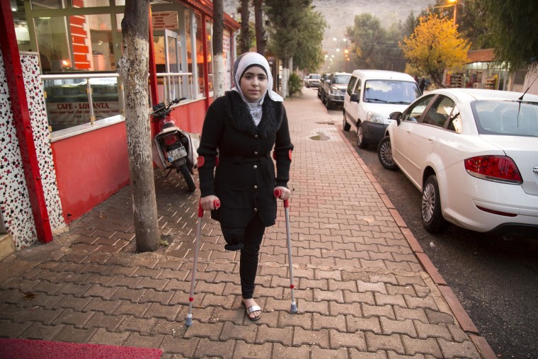 Noor stands on her crutches outside the hotel where her mother works in Reyhanli, southern Turkey.