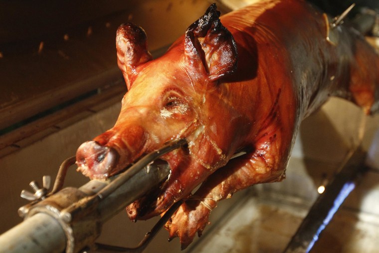 Image: A pig by Chef's Paella chef, Jorge Suarez, also known as "Chino" Chef Paella, who specializes in slow cooked pork, slow cooks in Paella's portable cooker at the customer's home in Miami, Florida