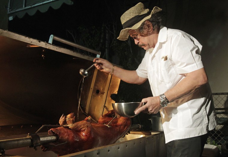 Image: Chef's Paella chef, Jorge Suarez, also known as "Chino" Chef Paella, who specializes in slow cooked pork, puts the finishing touches on an animal as it slow cooks in Paella's portable cooker at the customer's home in Miami, Florida