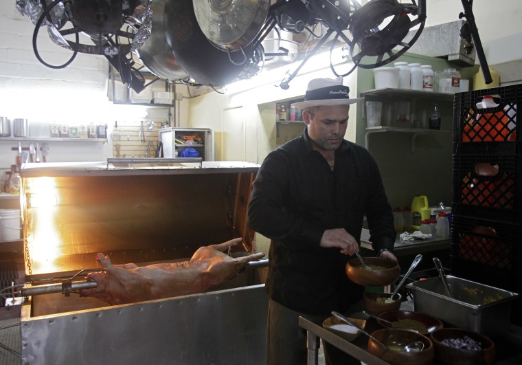 Image: Chef's Paella assistant chef Andres Roig prepares a pig at the company's kitchen in Miami, Florida