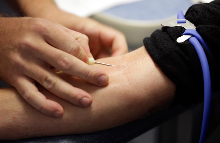 Image: A technician inserts a needle into a vein of a person as donating blood in Indianapolis