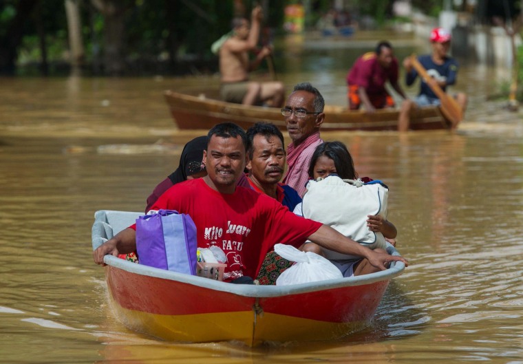 Image: A family ride on a boat through floodwater in Pengkalan Chepa