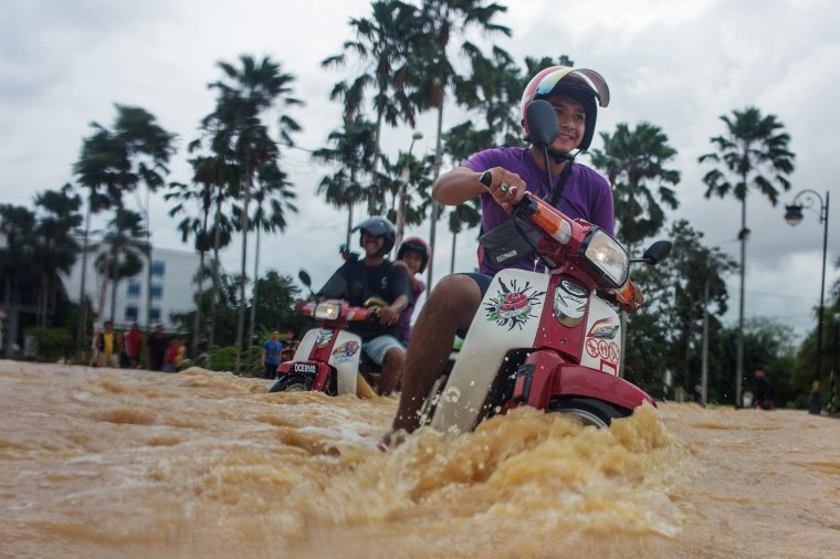Image: Local residents use their motorbikes to maneuver through floodwaters