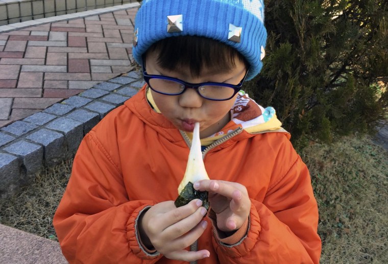 Image:  A boy eats a freshly pounded rice cake, or \"mochi,\"
