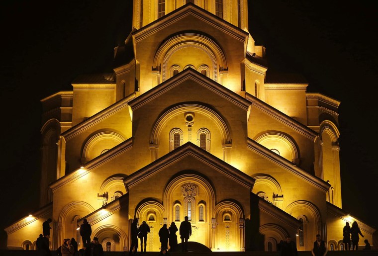 Image: People walk in front of the Holy Trinity Cathedral during midnight Christmas service in Tbilisi