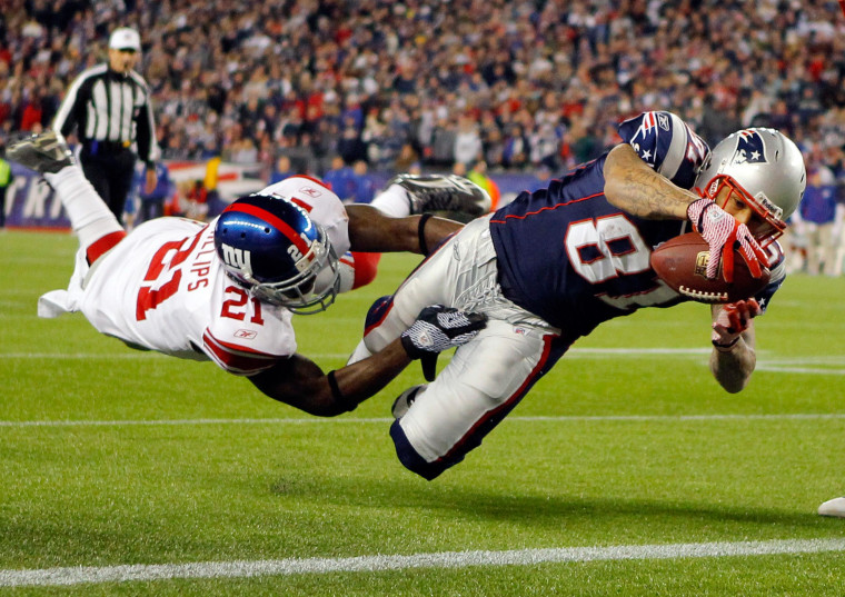 Image: Hernandez dives into the end zone for a touchdown through the arms of New York Giants strong safety Kenny Phillips during a game