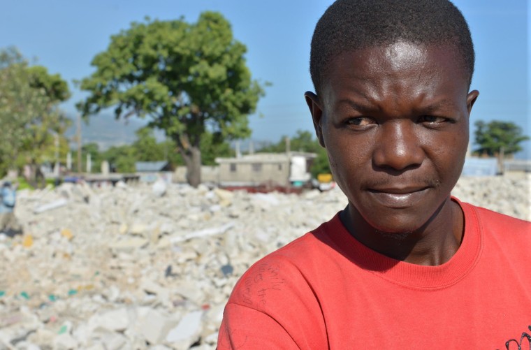 Image: Jean-Louis Wilner stands on the rubble of his demolished neighborhood in central Port-au-Prince, Haiti.