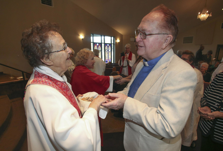 Image: Rita Lucey, left,  performs communion for Episcopalian Father Jim Coleman