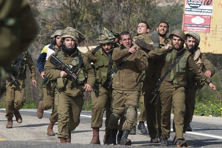 Image: Israeli soldiers carry a wounded comrade on a stretcher near Israel's border with Lebanon