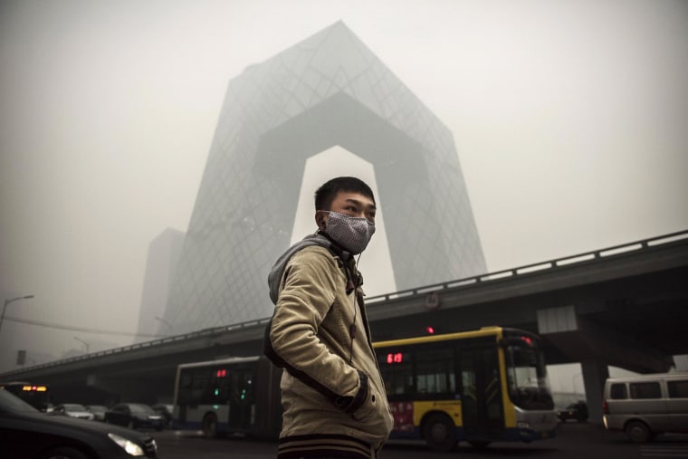 Image: A Chinese man wears a mask as he waits to cross the road