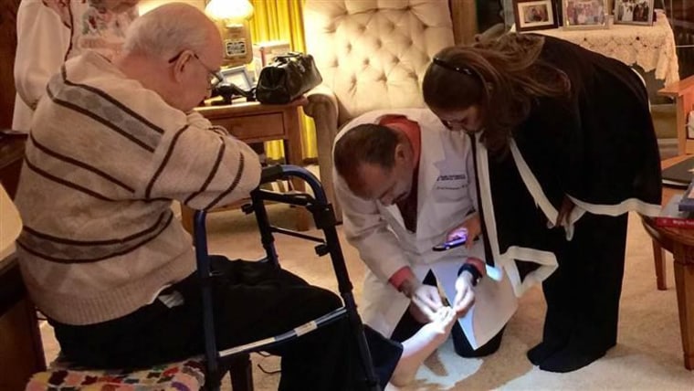 Dr. Fred Richardson examines a patient's foot during a house call.