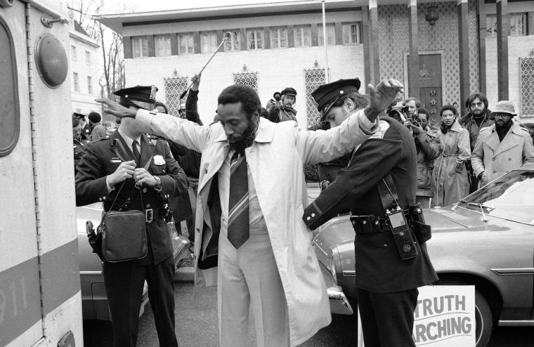 A policeman frisks human rights activist Dick Gregory following his arrest while picketing the South African embassy in Washington, Dec. 25, 1977. Gregory, and wife Lillian, were charged with demonstrating within 500 feet of an embassy. The two, along with a handful of supporters were protesting the South African regime's treatment of blacks.